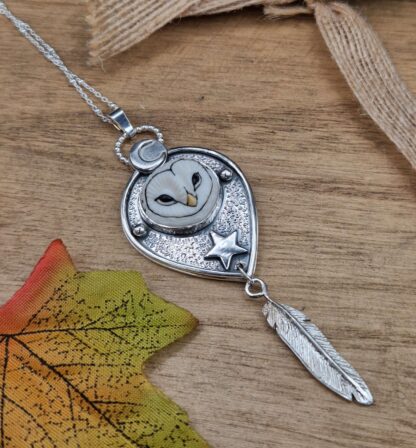 A silver owl pendant witha whimsical barn owl face